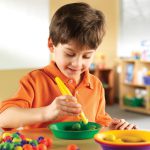 Child sorting toy fruits in to colours using the Learning Resources Easy Grip Children's Tweezers