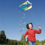 Child flying a mattress kite in a field