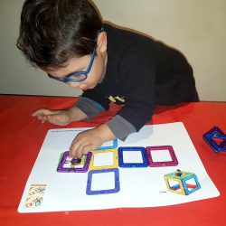 child laying out square magformer's pieces on a 2d plan