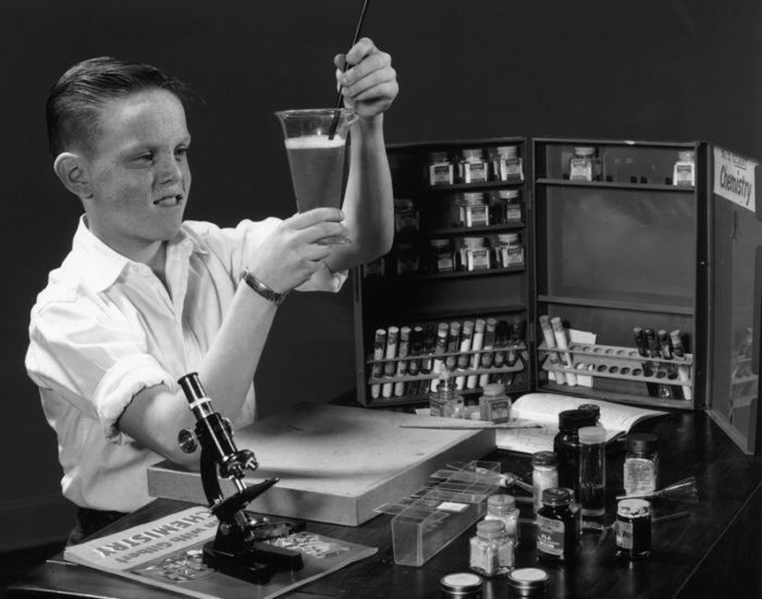 Retro image of a child playing with a classic microscope and science kit