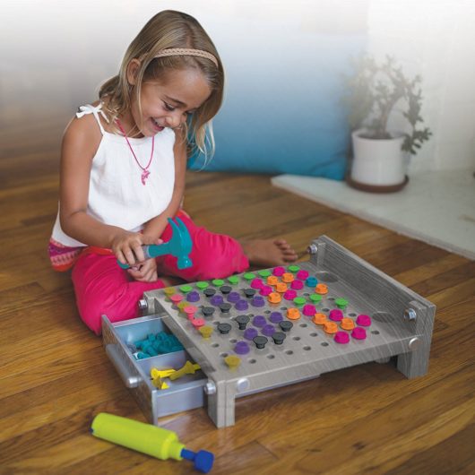 Girl hammering nails into Educational Essentials My First Workbench