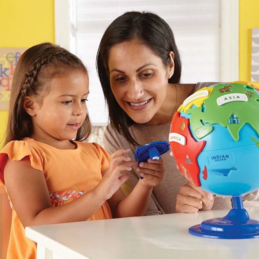 A mother helps her child examine and learn the continent shapes